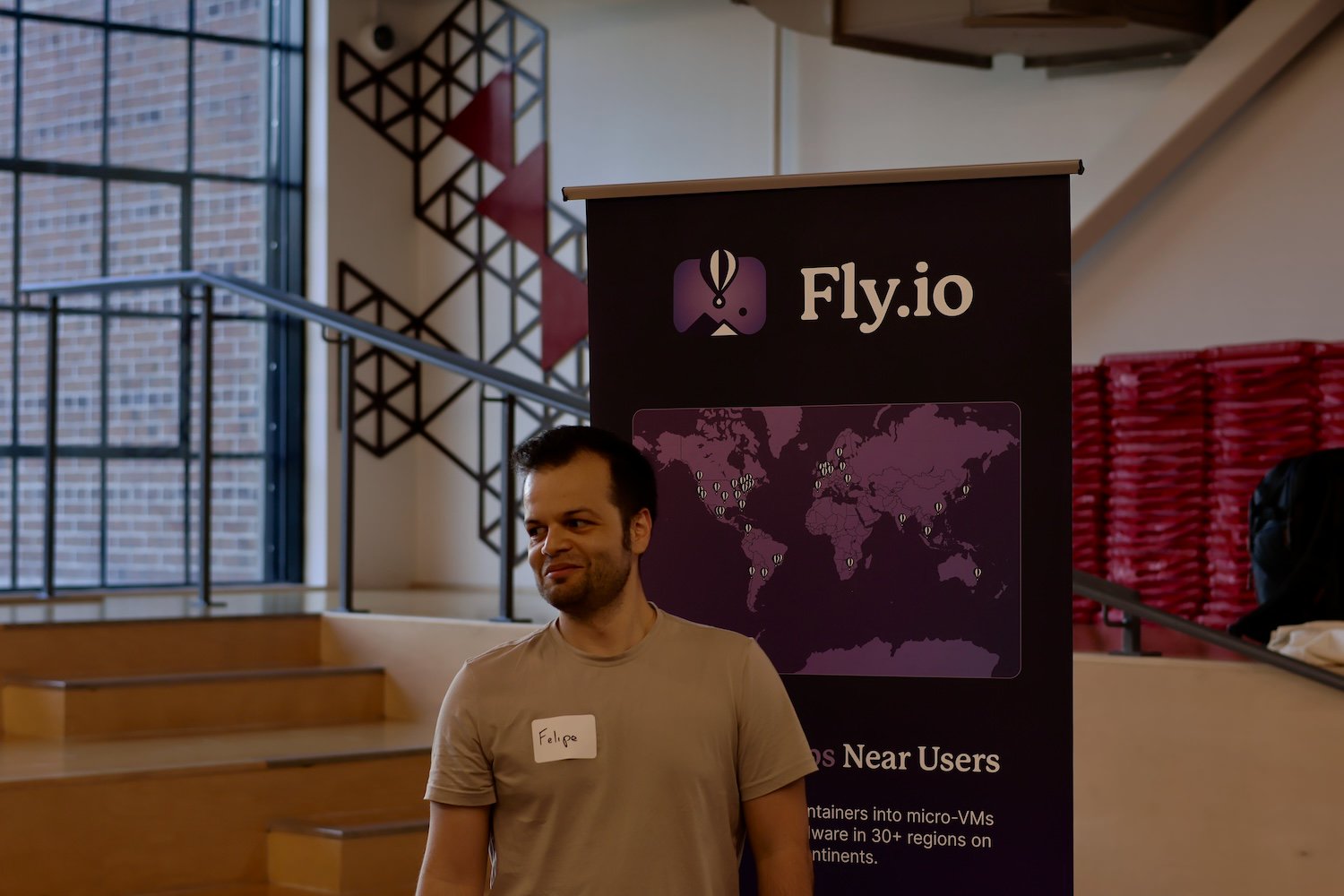 A person standing happily in front of a fly.io banner.