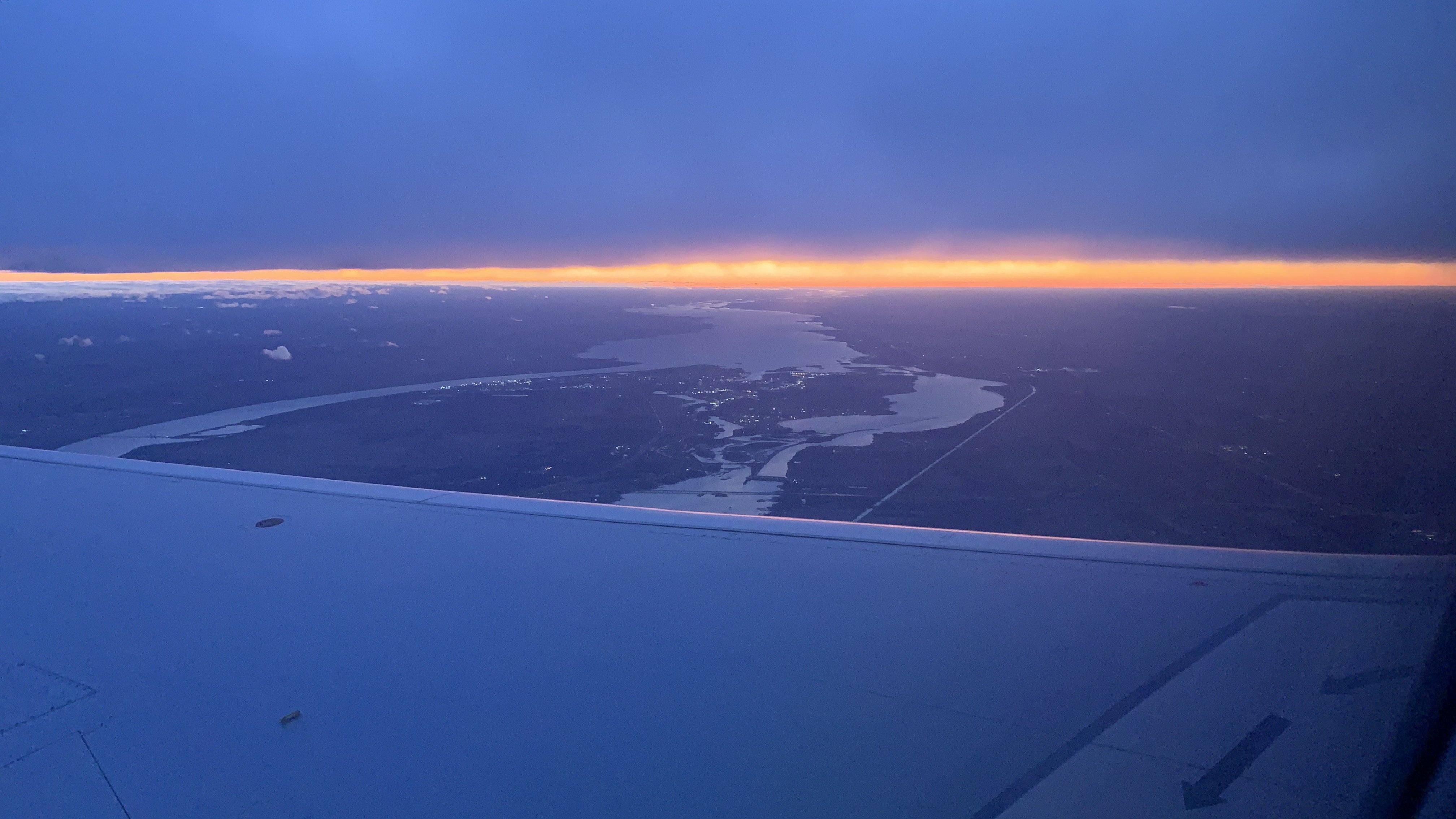 An image of A photo of the sun setting, taken from an airplane