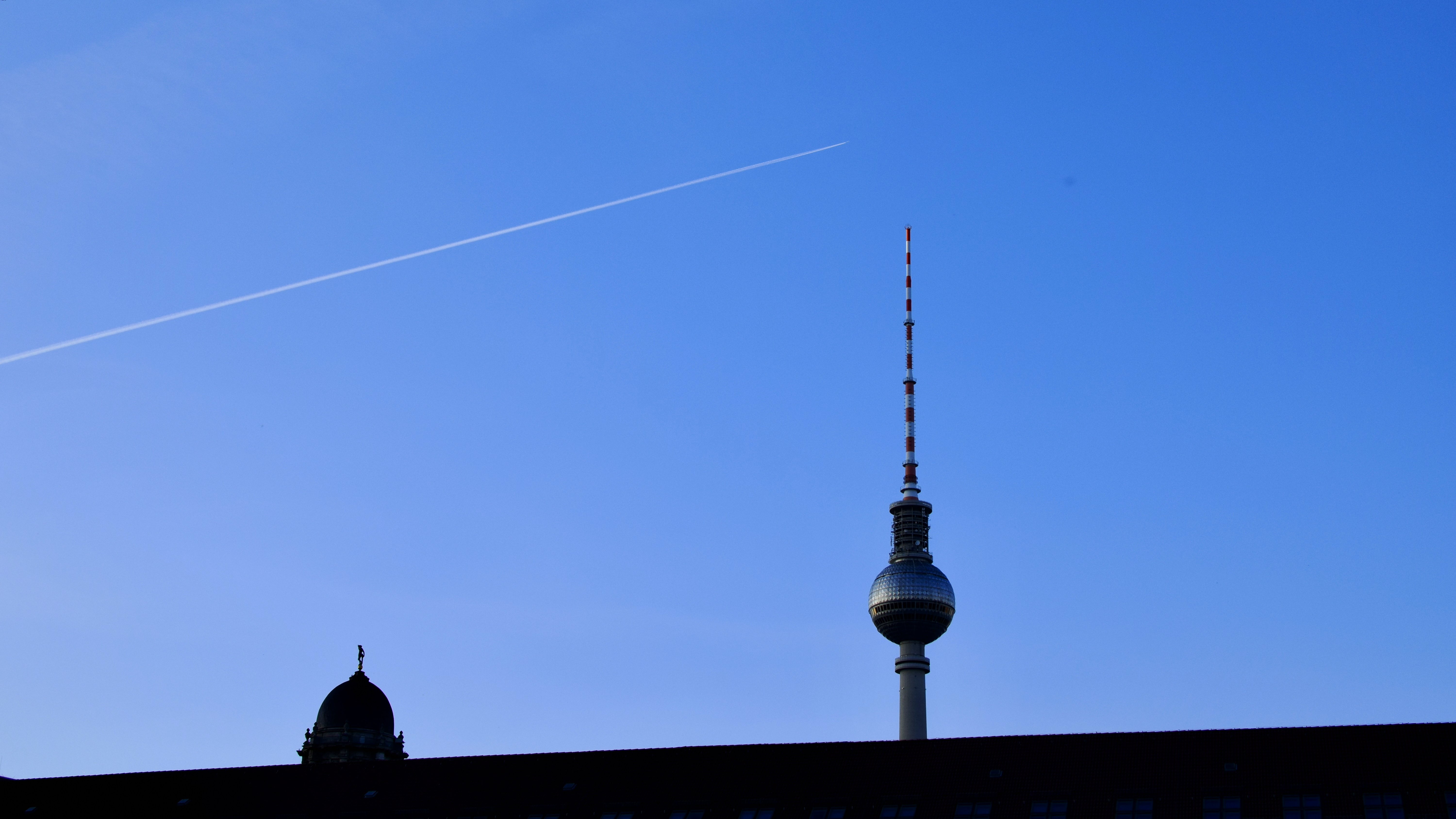 An image of An airplane contrail above the Berlin TV tower near sunset