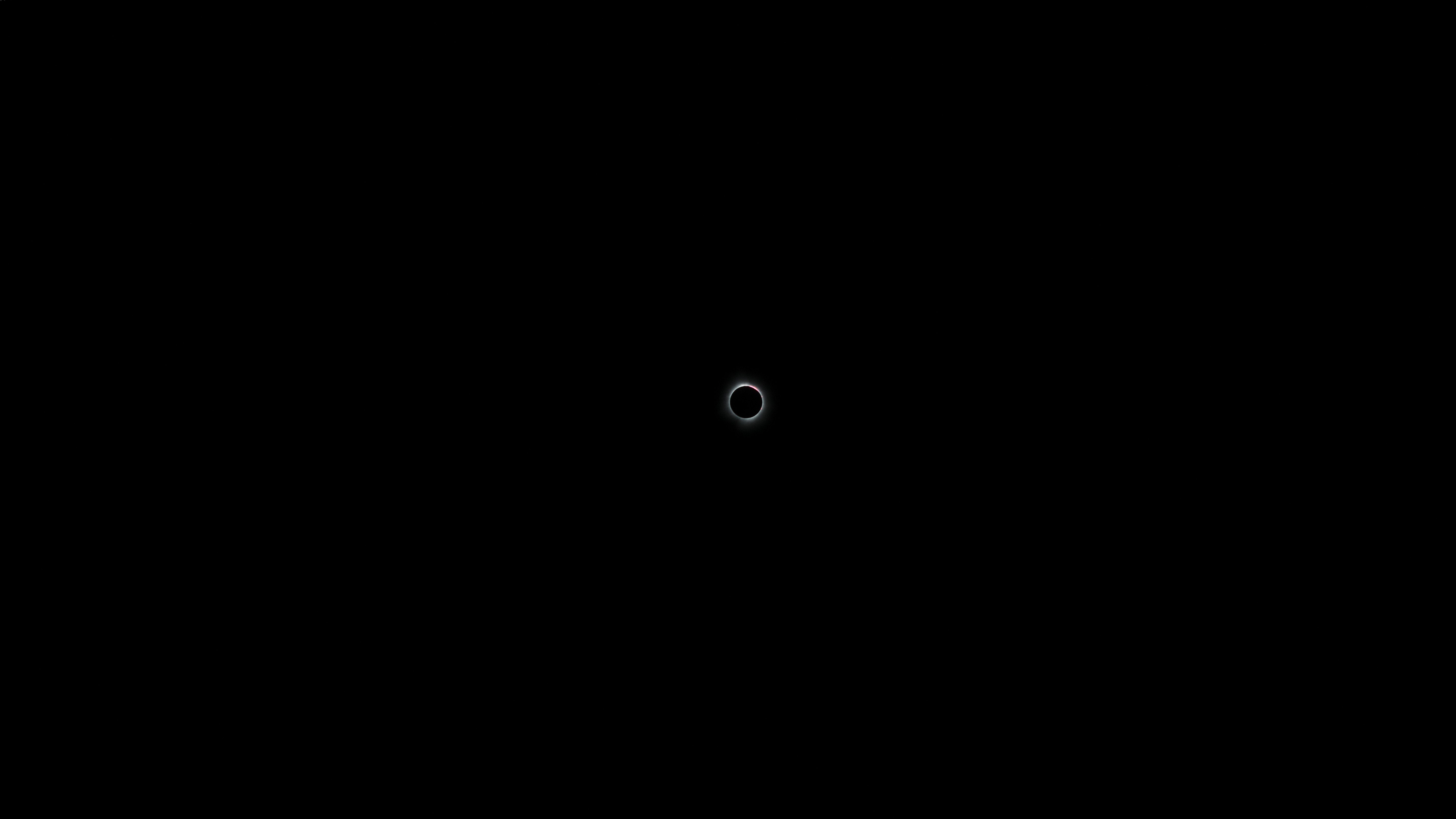An image of The solar eclipse, if you look closely you can see a pink blob, that's a coronal mass ejection