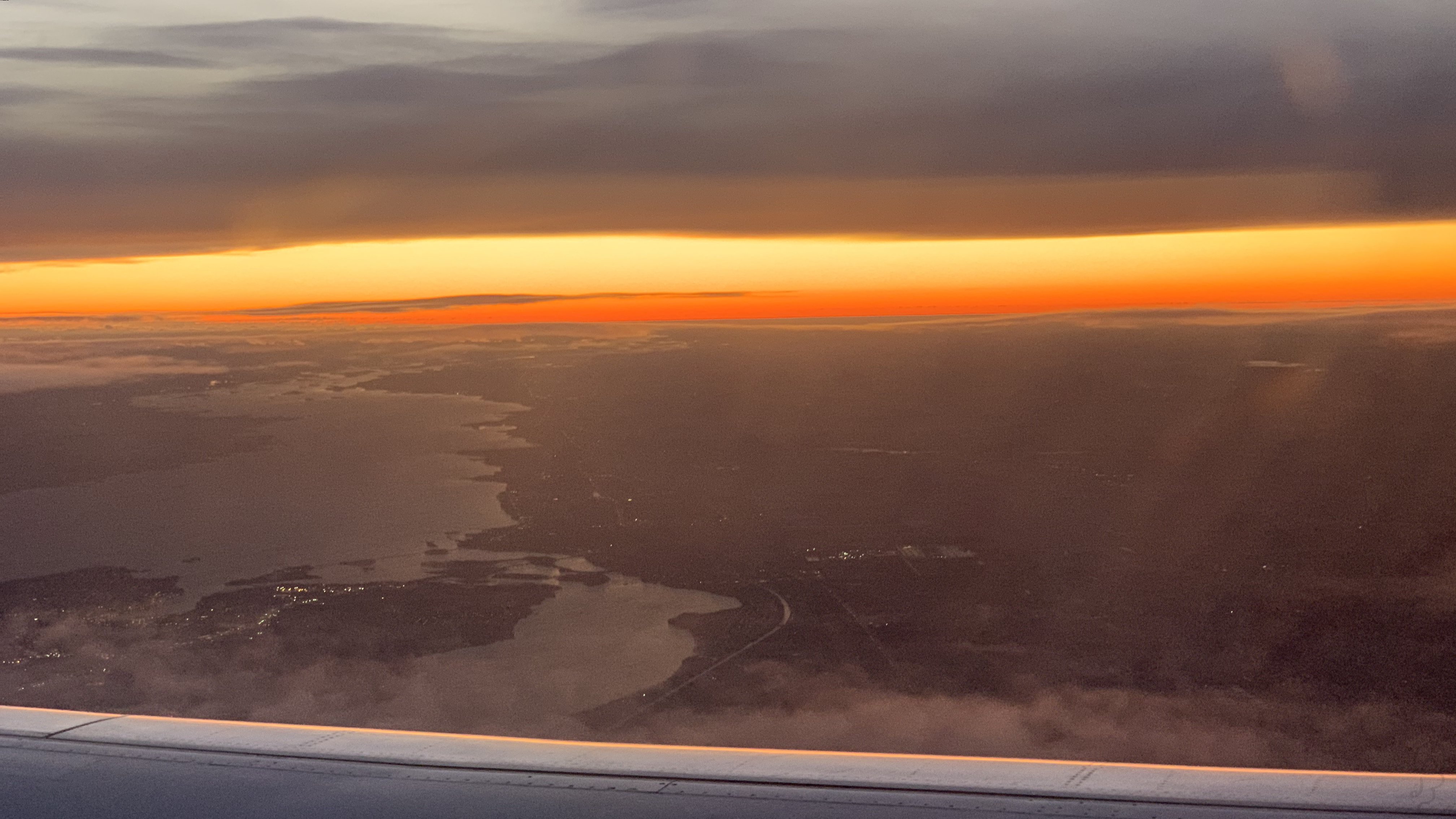 An image of A photo of the sunset taken from an airplane, it looks like night is breaking into the sky.