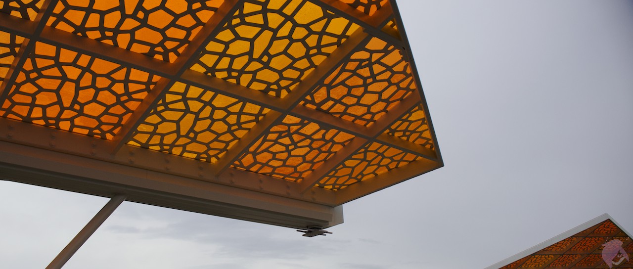 An image of Light filtered from a gray overcast sky through a shield of orange stained glass.