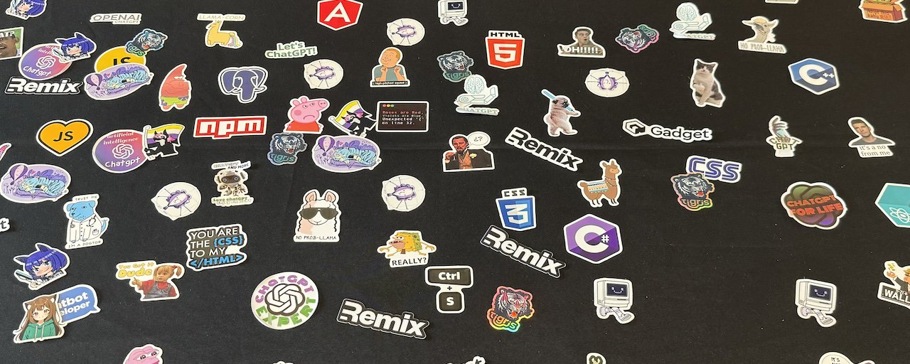 An image of A table showing a variety of stickers, some from fly.io, some generic AI stickers, some for Remix, and some for the Xe Iaso Dot Net Cinematic Universe