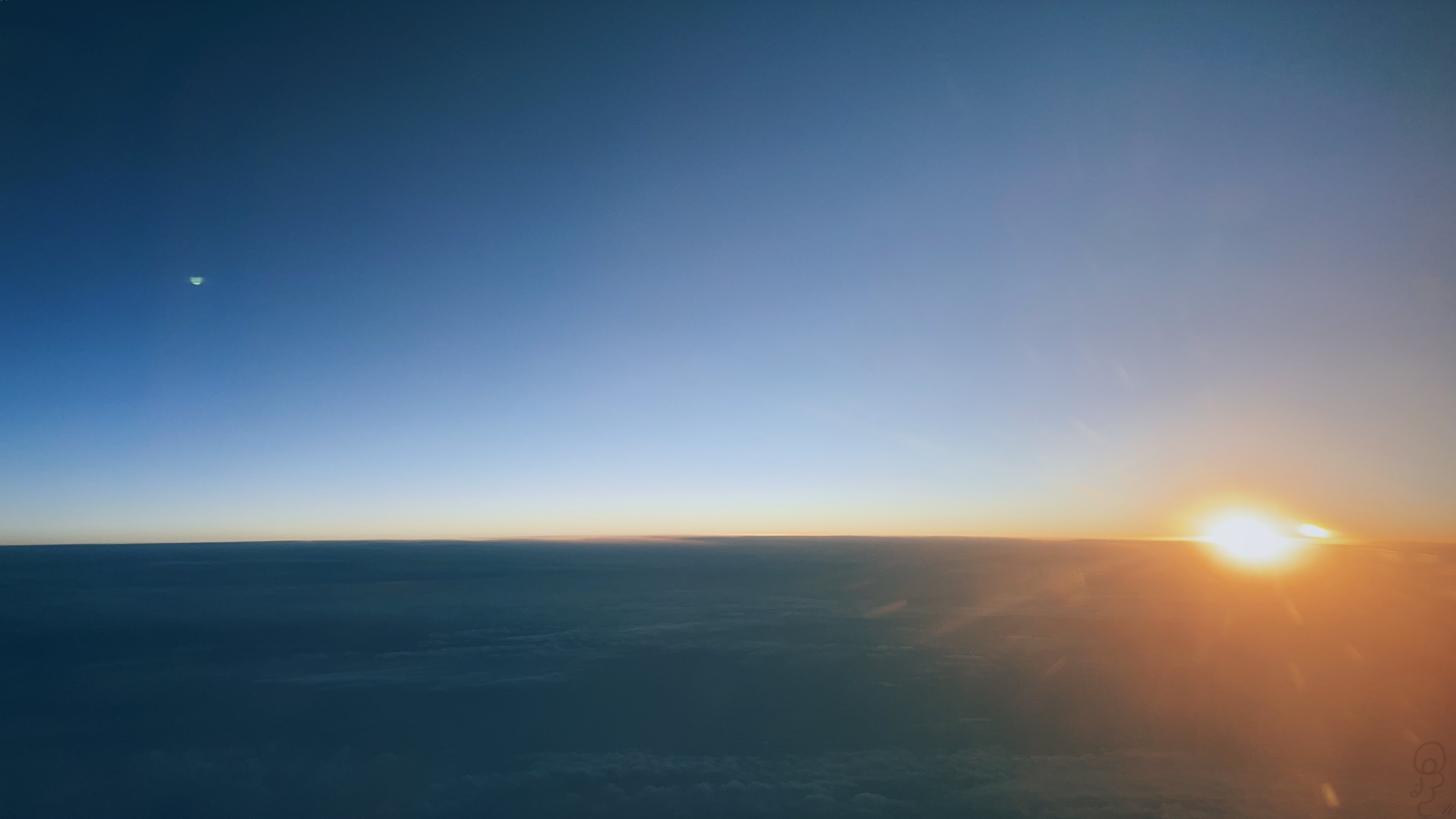 An image of The sun bursting into the sky at daybreak, taken from a plane.